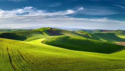 Obraz premium Scenic view of rolling green hills bathed in sunlight under a cloudy sky, creating a serene and picturesque landscape