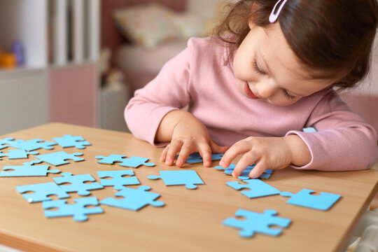 Cute little child girl doing puzzle at home, children development