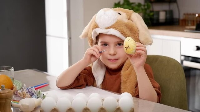 Young girl wearing bunny hat painting eggs for easter celebration
