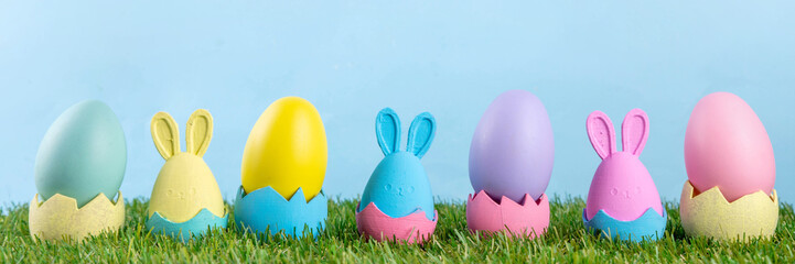 Easter tradition celebration, preparation for Easter egg hunting, invitation to children's morning party background. Colorful decor bunnies and Easter eggs in grass and blue background, copy space