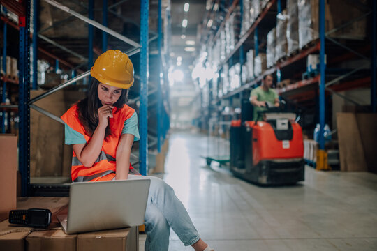 Female warehouse worker using laptop and thinking about logistics