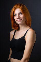 Naklejka premium Cute red-haired girl, studio portrait on a black background.