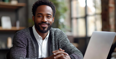 Remote worker smiling confidently while working on laptop in modern home office environment