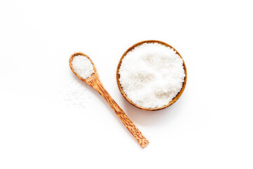 Coarse sea salt in a wooden and spoon, top view. Salt for spa, salt baths or cooking