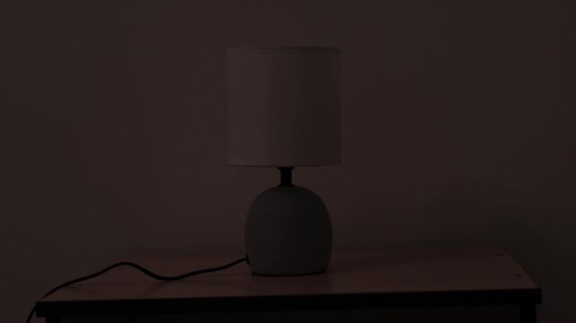 People is turning on and off modern night table lamp switch. Warm lighting for bedside lamp for reading books. Close up.