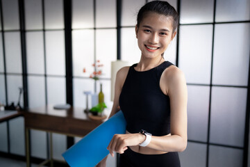 Sporty asian woman in sportswear with health app&nbsp;on smart watch and Yoga mat&nbsp;after training&nbsp;Exercise wellness health sportswoman wellness health rolling Yoga mat&nbsp;after training&nbsp;