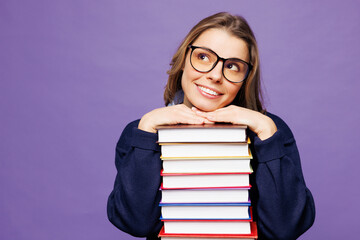 Young pensive dreamful girl student wears blue casual clothes glasses hold stack of books look...