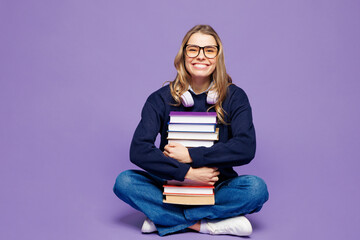Full body young smiling happy girl student wear blue casual clothes glasses sitting hold stack of...