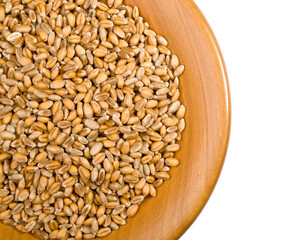 Wooden bowl overflowing with whole wheat berries on white background