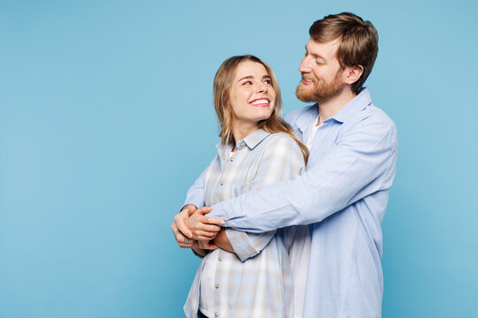Side profile view young couple two friends family man woman wears shirt casual clothes cuddle embrace together isolated on pastel plain light blue cyan background studio portrait. Lifestyle concept.