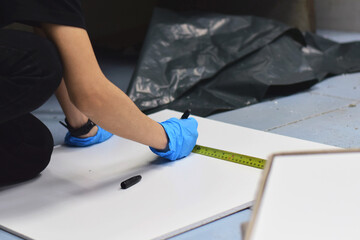 The technician is using a measuring tape to measure the ceiling.