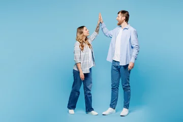 Gordijnen Full body young fun couple two friends family man woman wear shirt casual clothes meeting together greeting giving high five clapping hands folded isolated on plain blue background. Lifestyle concept. © ViDi Studio