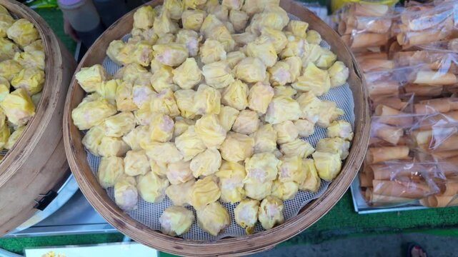 A steaming batch of Kanom Jeeb Thai dumplings captured from a top-down view, with hot steam rising and slightly fogging the camera lens.