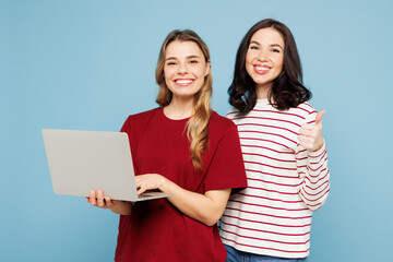 Young IT couple two friends women wearing red casual clothes together hold use work on laptop pc computer showing thumb up isolated on pastel plain light blue cyan background studio Lifestyle concept
