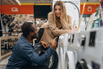 Man and woman are choosing washing machine in the store
