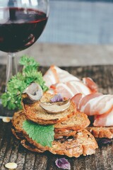 toast with fried mushrooms and bacon and greens with a glass of red wine on a wooden table