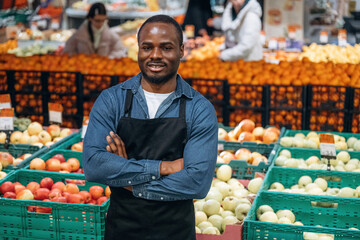 Grocery store worker in apron is near products