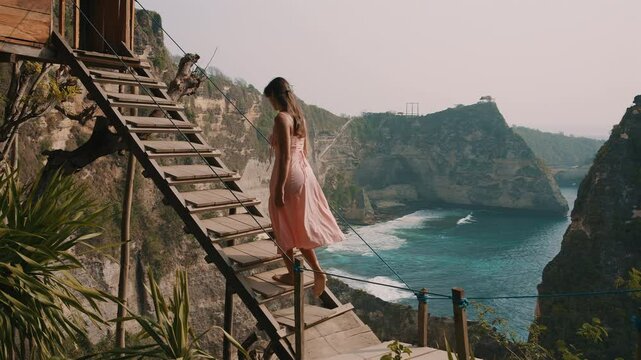 Female walks up stairs of famous tree house, Nusa Penida, Bali
