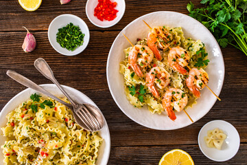 Pasta with grilled shrimps, garlic and parsley on wooden table	
