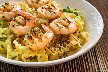 Pasta with grilled shrimps, garlic and parsley on wooden table	
