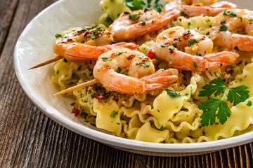 Pasta with grilled shrimps, garlic and parsley on wooden table	