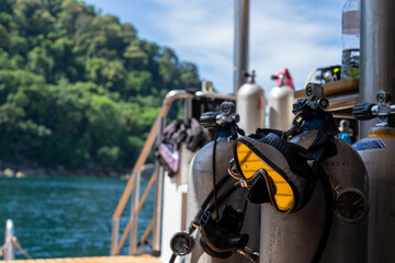 Diving equipment on a liveaboard with an Island in the Background. A mask is hanging on a airtank 