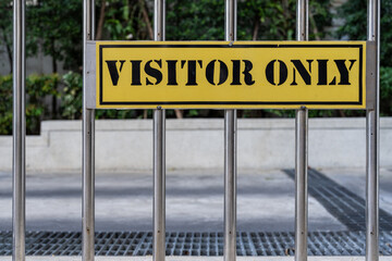 A yellow sign on bars with the text «Visitor Only»