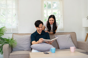 Joyful couple sharing a moment on the couch, exploring a book together in a cozy living room.
