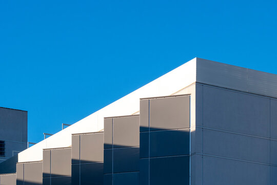 Minimalist architectural structure with clean lines and reflective windows, showcasing contemporary urban aesthetics under a blue sky.