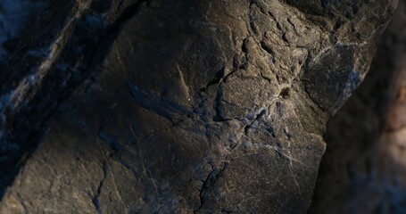 Dark Rock Surface with Cracks and Light Contrast