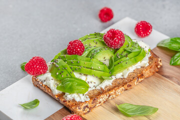 Whole wheat bread with avocado, raspberries, cream cheese and chia seeds, copy space, top view