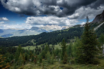 Fototapeta premium Majestic view of the Dolomites with dramatic clouds and lush greenery in the Alps of Italy during late afternoon