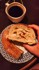 Woman holding slice of sweet bread during breakfast with coffee in croatia