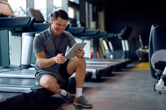 Happy personal trainer using digital tablet while working in gym. - Powered by Adobe
