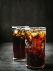 Cola soft drink with ice cubes, soda fizzy drink in Cold two glass on gray background