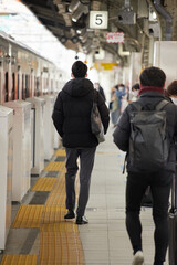 Fototapeta premium 冬の駅のホームで電車待ちのサラリーマンたちの姿