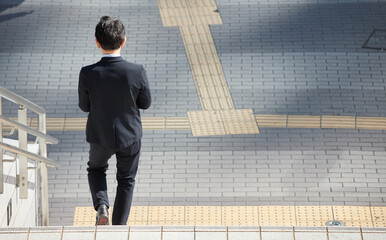 冬の昼の都市の街で階段を降りる中年サラリーマンの姿