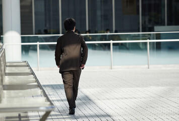 冬の昼の都市のオフィス街で歩く一人のサラリーマンの姿