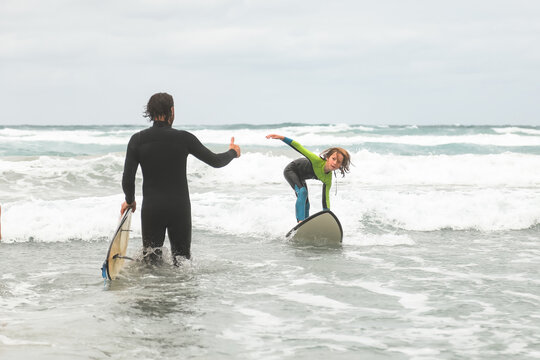 Man giving boy thumbs up while learning to surf