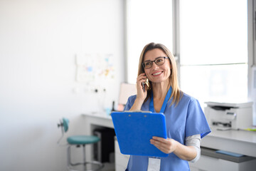 Friendly nurse a modern medical clinic making phone call with patient.