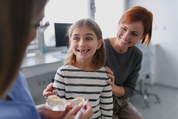 Girl showing her lost tooth to the dentist during a routine checkup at the dental clinic.