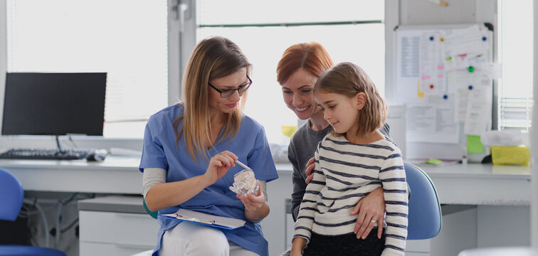 Girl showing her lost tooth to the dentist during a routine checkup at the dental clinic.
