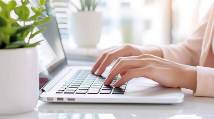 Female hands are typing on laptop keyboard in modern office with plants, working productively on computer