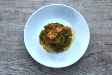 spicy stir fried slice yard long bean with fat pork and lemon grass in curry sauce on plate