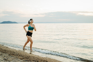 Young caucasian woman run or jog on the beach at sunset	