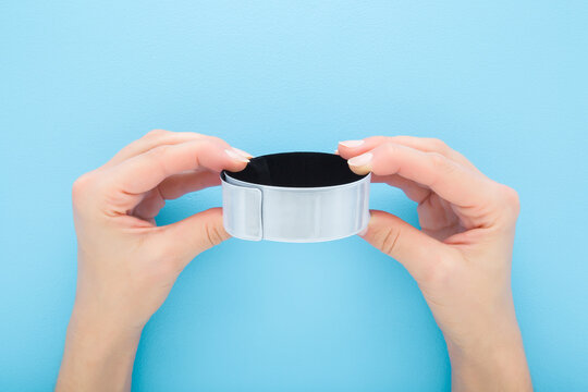 Young adult woman hand fingers holding and showing light gray reflective tape on light blue table background. Pastel color. Closeup. Point of view shot. Top down view.