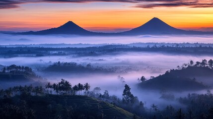 Fototapeta premium Misty sunrise over twin volcanic peaks and valley.