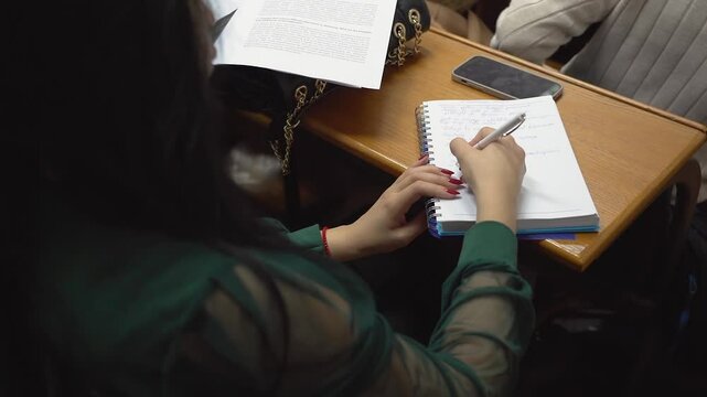 A student is taking notes in a lecture at the university close up