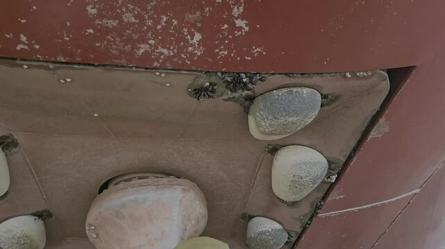 Thruster foundation under ship hull in drydock with worn zinc anodes and marine growth. Slow panning shot