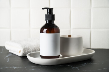 Shampoo bottle, towel and hairbrush in the bathroom.